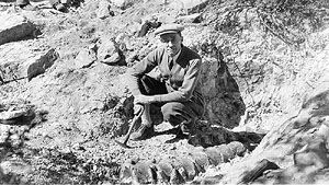 Black and white image of a man, Frederick Kessler, posing with dinosaur vertebrae. Circa 1932.